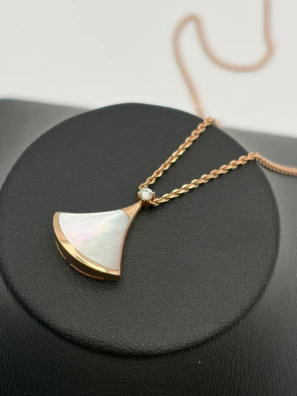 Counterfeit Bulgari Divas' Dream necklace with a mother-of-pearl fan pendant and diamond, resting on a black display tray