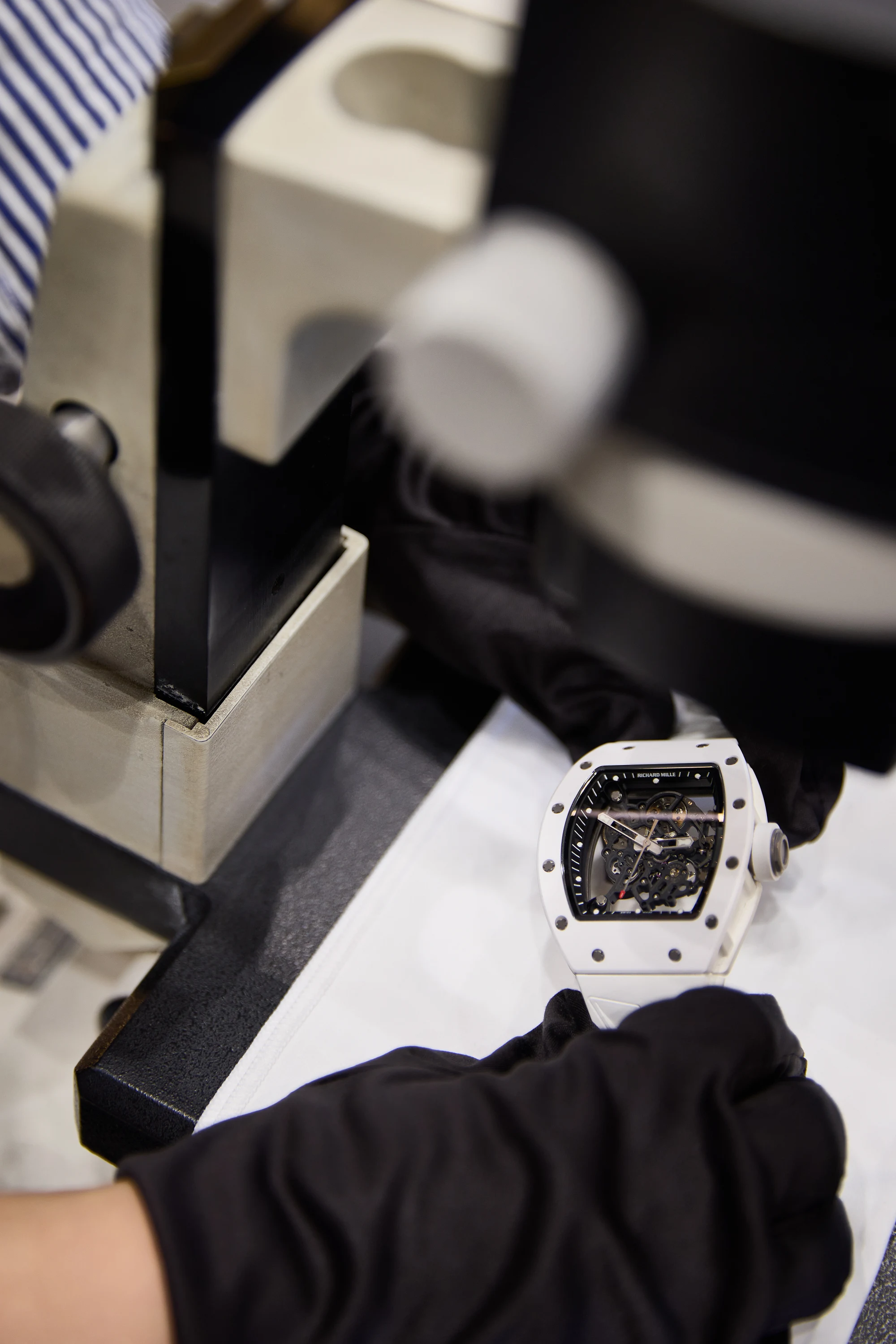 A Richard Mille watch being inspected with gloves under a bench light