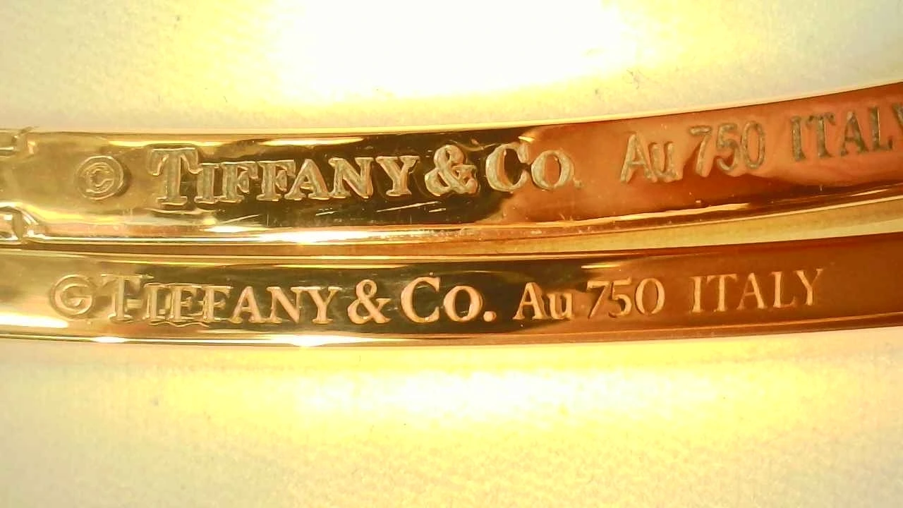 Stacked comparison of a fake (press-stamped, crooked) and genuine (laser-engraved) Tiffany T1 bangle hallmark