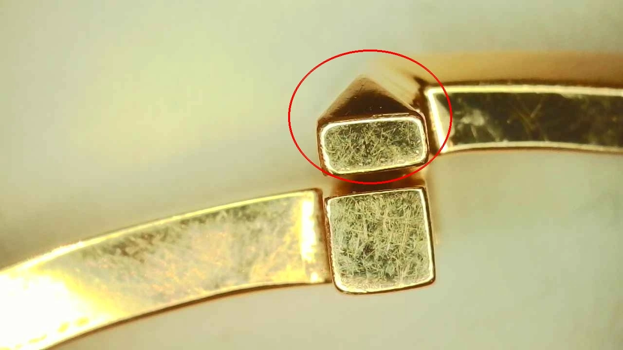 Counterfeit Tiffany T1 bangle clasp release button, circled to show its rectangular shape instead of the genuine cube shape