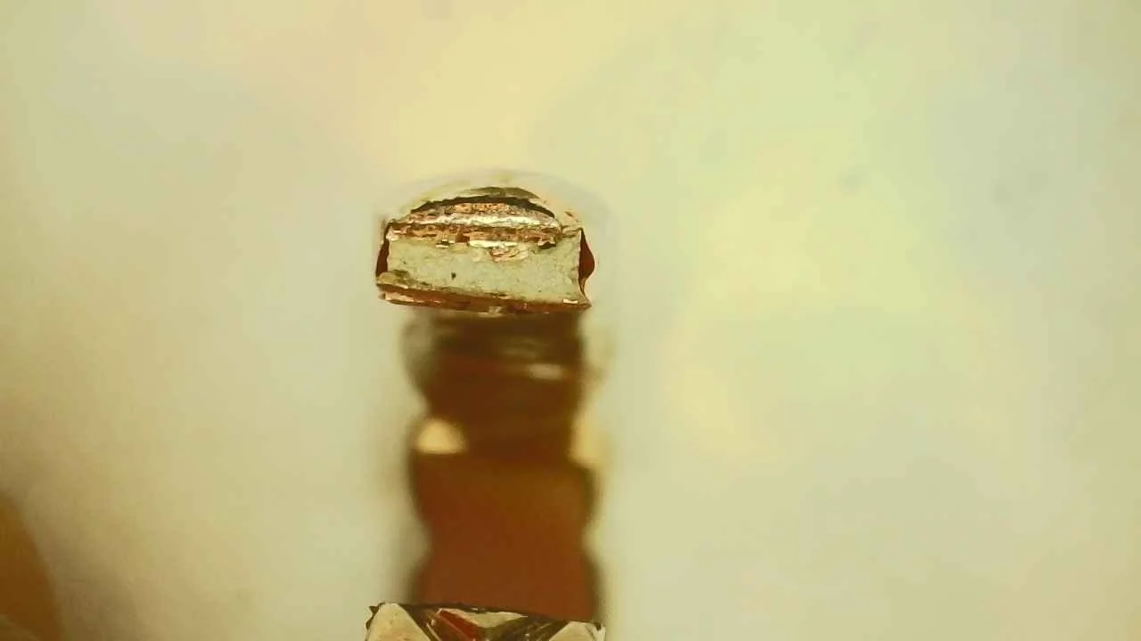 Cross-section of a counterfeit Chanel Coco Crush Mini ring showing chalky white filler under gold-colored plating