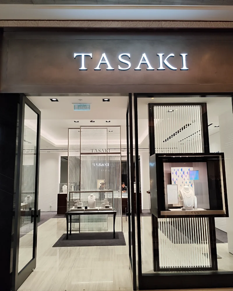 TASAKI boutique entrance with the illuminated TASAKI logo above glass doors and pearl jewelry display windows, Galaxy Macau