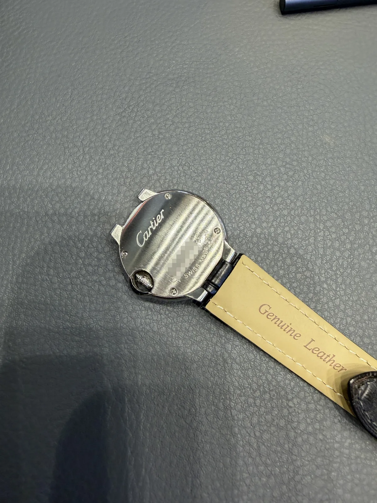 Closed case back of the watch with the Cartier script and engravings, serial number blurred