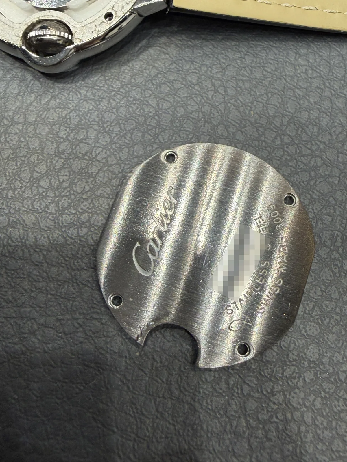 Removed case back showing the Cartier script and engravings, serial number blurred