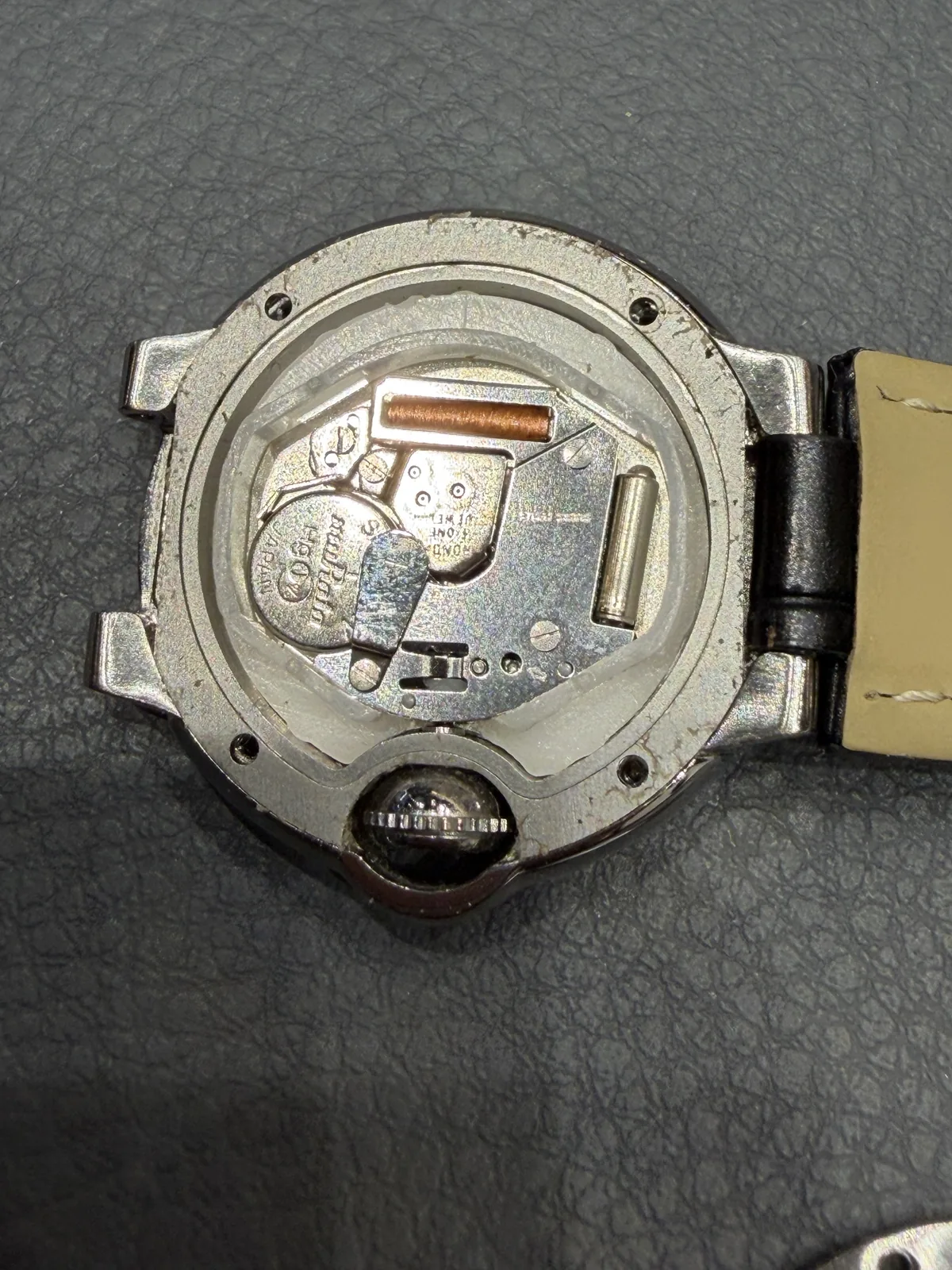 Quartz movement inside the opened case back of the watch, held in place by a white plastic spacer