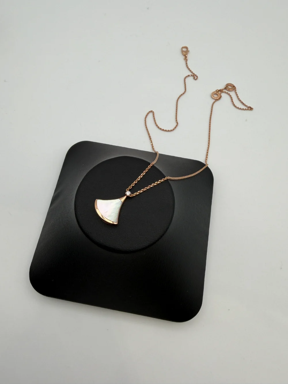The counterfeit Divas' Dream necklace laid out on a black tray, chain trailing behind the pendant